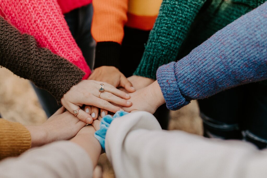 Many hands joined in a “go team” gesture